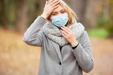 Cold and flu. Woman with a medical face mask at outdoorの写真素材