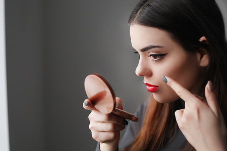 Beautiful woman looking in the mirror in the morningの写真素材