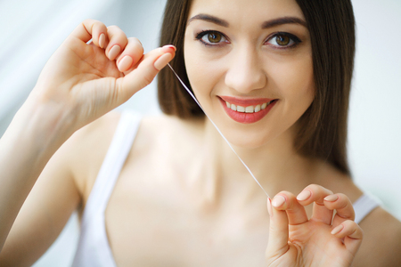 Teeth Care. Beautiful Smiling Woman Flossing Healthy White Teeth. High Resolution Imageの写真素材