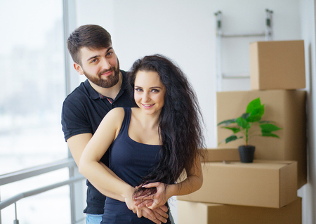Happy young couple moving in new home unpacking boxes
