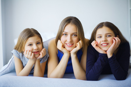 Happy family on the bed. Children with their mother in the bedroom.の写真素材