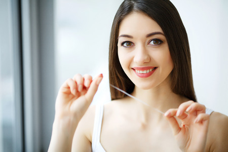 Teeth Care. Beautiful Smiling Woman Flossing Healthy White Teeth. High Resolution Imageの写真素材