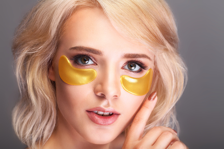 Patch Under Eyes. Beautiful Woman Face With Gold Hydrogel Patches, Lifting Anti-Wrinkle Collagen Mask On Fresh Healthy Facial Skin. High Resolutionの写真素材