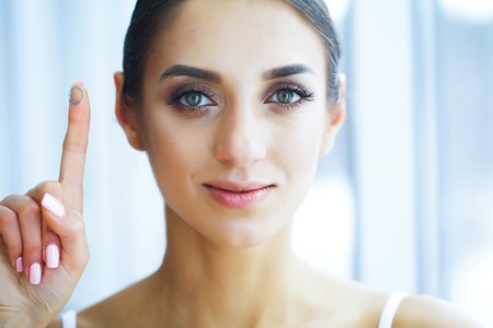 Health and Beauty. Beautiful Young Girl with Contact Lenses. Woman Holds Green Contact Lens on Her Finger. Healthy View. High Resolutionの写真素材