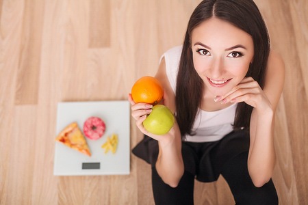 Sport woman holding an apple in one hand and donut in other handの写真素材