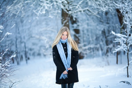 Winter. Young girl walking snowy forest and smiling at the camera. Great mood.の写真素材