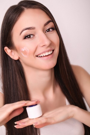 Beautiful Young Woman with clean fresh skin touch face . Facial treatment , cosmetology , beauty and spaの写真素材