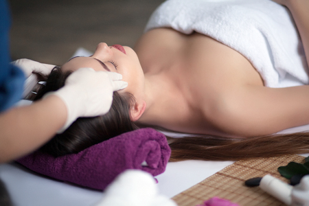 Girl massage therapist doing head massage beautiful brunette girlの写真素材