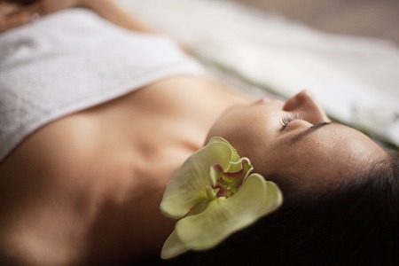 beautiful girl in a beauty salon with orchid flower in her hair. spa treatments. close-upの写真素材