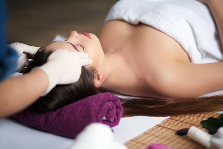 Beautiful young girl having face massage in spa salonの写真素材