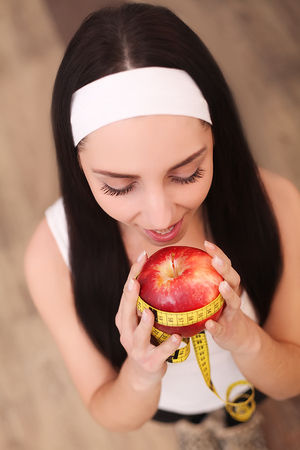 Healthy happy woman with apple and tape measure for diet and weight loss conceptの写真素材