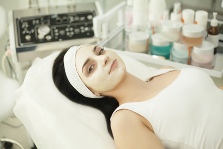Beautiful young woman getting facial massage lying on the couch. Top view focused on the faceの写真素材