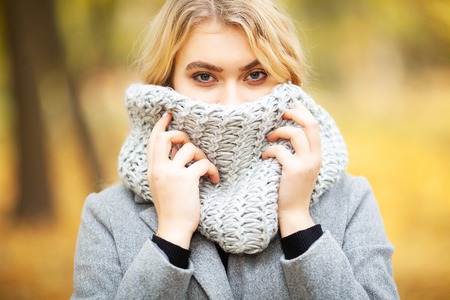 Cold autumn. Woman walking in park feeling coldの写真素材
