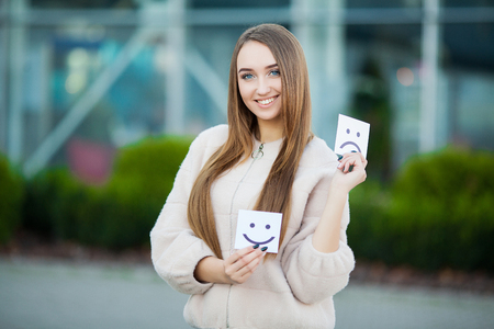 Beautiful woman holding cards with sad and funny smileの写真素材