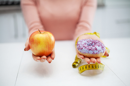Dieting concept. Young Woman choosing between Fruits and Sweetsの写真素材