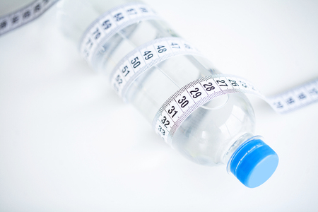 Diet Concept. Bottle With Measure Tape On White Kitchen Tableの写真素材