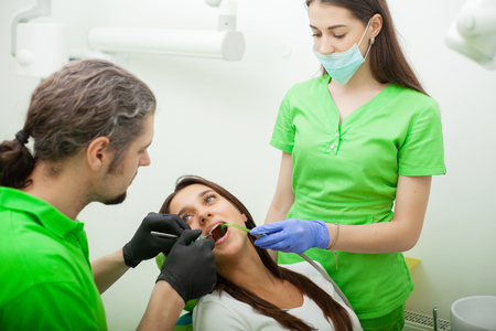 The dentist man are treating teeth to client in dental officeの写真素材
