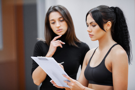 Woman fitness coach writes a training program for the clients fitness clubの写真素材