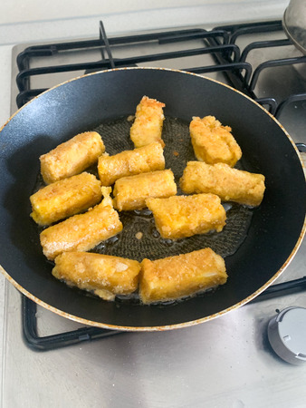Fried mozzarella cheese sticks breaded on frying pan