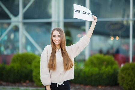 Businesswoman with long Hair Holding a sign Board with a Welcome has Airport Backgroundの写真素材