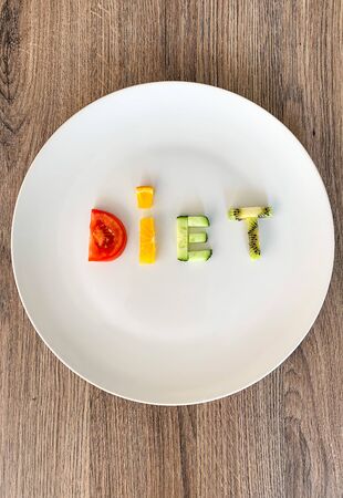 Word DIET made of sliced vegetables in white plate on wood background.の写真素材