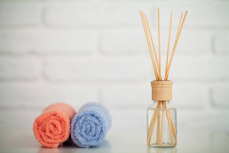 Fluffy bath towels on light wooden table with aroma sticks