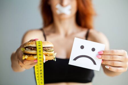 Harmful food. The choice between malicious food and sport. Beautiful young girl on a diet. The...