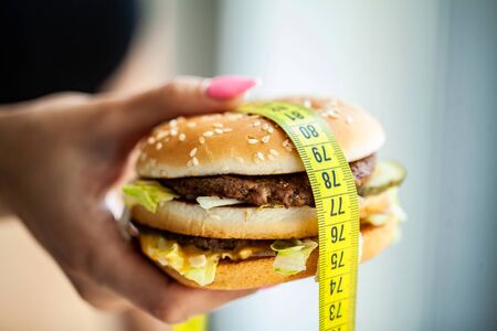 Harmful food. The choice between malicious food and sport. Beautiful young girl on a diet. The concept of beauty and health. On a gray backgroundの写真素材