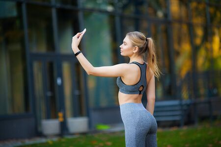 Sportswoman taking a break after workout and using phone outdoorsの写真素材