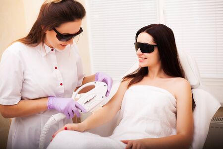 Body Care. Woman getting electric hair removal treatment on her hand from a beauticianの写真素材
