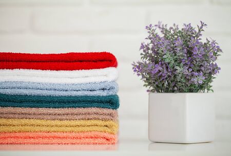 Fluffy bath towels on light wooden table with decor and white backgroundの写真素材