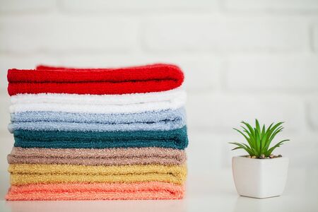 Fluffy bath towels on light wooden table with decor and white backgroundの写真素材
