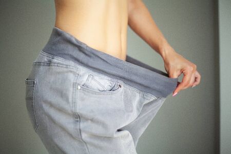 Diet concept. Slim girl after diet in old big jeansの写真素材