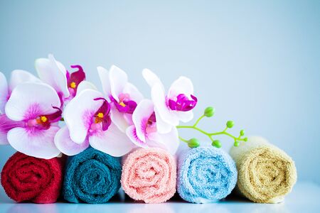 Colored towels and orchid on white table with copy space on bath room background.の写真素材