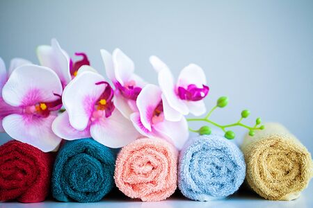 Colored towels and orchid on white table with copy space on bath room background.の写真素材