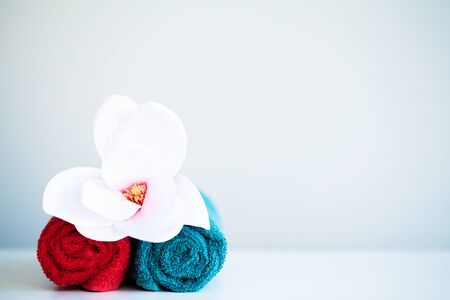 Colored towels and orchid on white table with copy space on bath room background.の写真素材