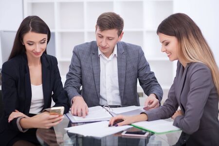 Meeting with agent in office, buying renting apartment or house, buyers of real estate ready to conclude a deal, family couple shaking hands with realtor after signing documents for realty purchaseの写真素材