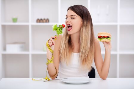 Attractive young woman makes a choice between healthy and unhealの写真素材