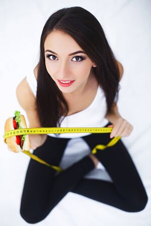 Sporty smiling attractive woman having vegetarian lunch at the kitchen, enjoying healthy food, getting energy for sport and study, wearing white sportswear top,の写真素材