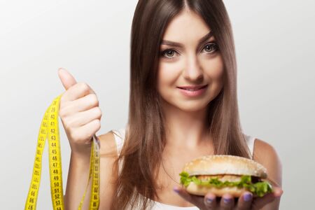 Hands offer an apple healthy food and cakes unhealthy food to each other. The concept of choice: healthy low-calorie or unhealthy high-calorie meals On a gray background.の写真素材