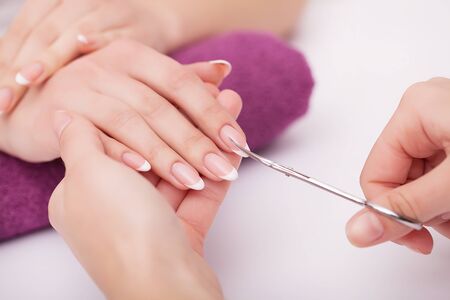 Nail Care And Manicure. Closeup Of Beautiful Female Hands Applying Transparent Nail Polish On Healthy Natural Womans Nails In Beauty Salon. Manicurist Hand Painting Clients Nails. High Resolutionの写真素材