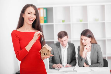 Young smiling couple about to sign a house renting agreement, happy to buy new apartment, meeting in the office with a trusted, reliable real estate agent, confident in creditの写真素材