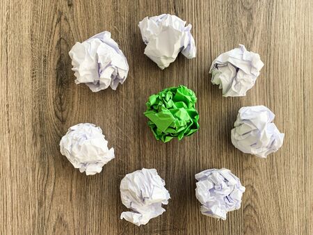 Crumpled green paper ball among white balls.の写真素材