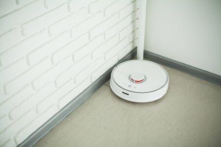 Smart House. Vacuum cleaner robot runs on wood floor in a living room.