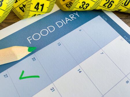 Diet plan concept. Measuring tape and diet plan on wooden background