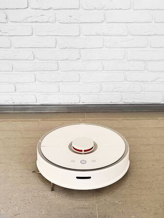 Smart House. Vacuum cleaner robot runs on floor in a living room.の写真素材