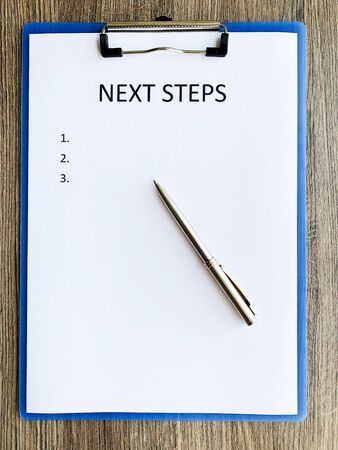 Clipboard with text next step on wood desk.の写真素材