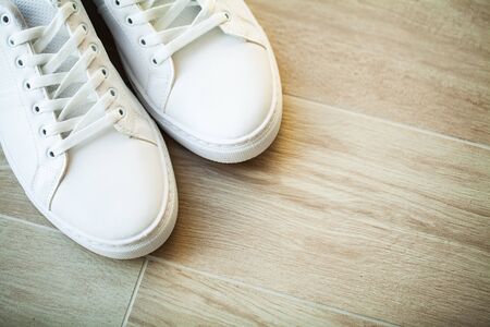 Pair of new stylish white sneakers on wood floor.の写真素材
