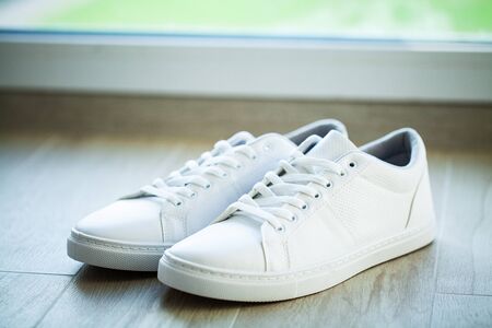 Pair of new stylish white sneakers on wood floor.の写真素材