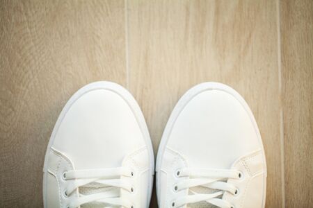 Pair of new stylish white sneakers on wood floor.の写真素材